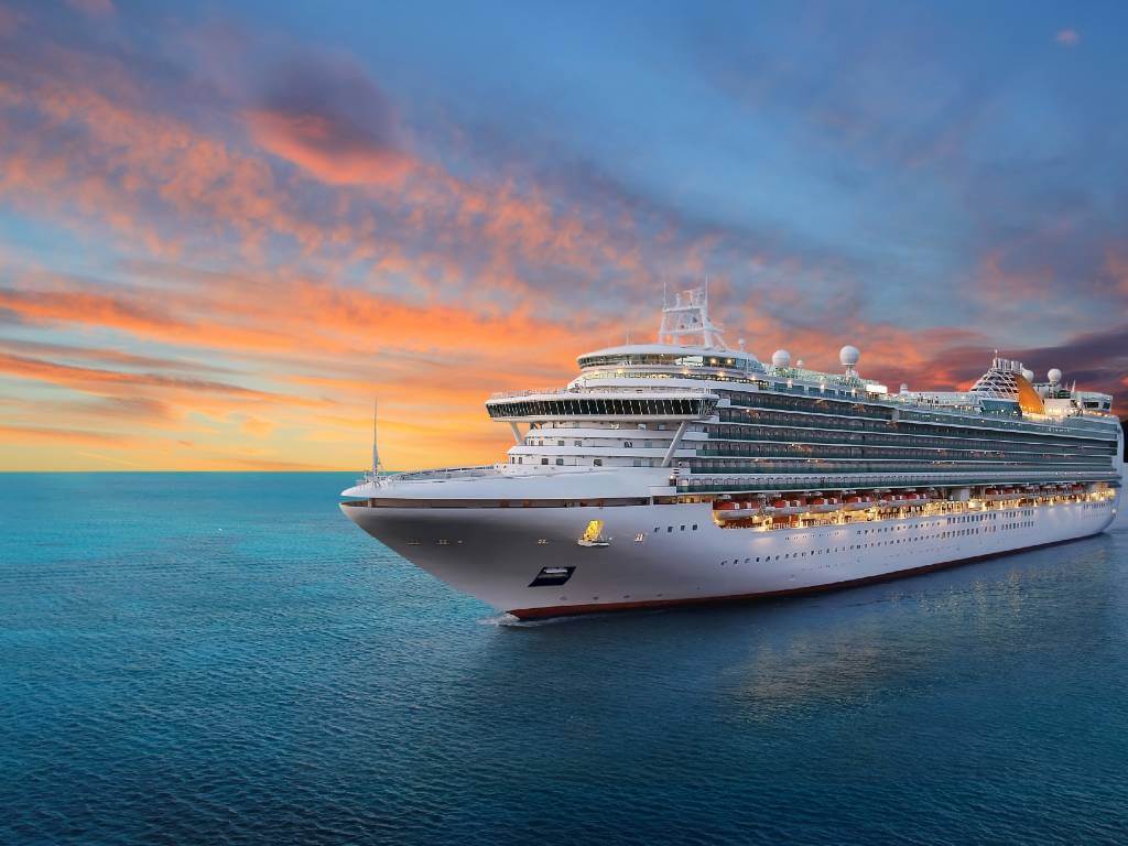cruise ship with sun set behind it